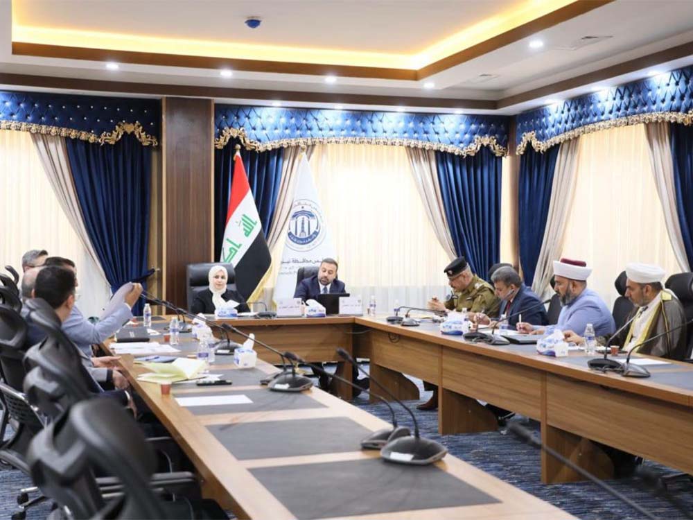 اجتماع رسمي موسّع داخل مجلس محافظة نينوى بحضور أعضاء من لجنة الأوقاف وممثلين عن جهات دينية وأمنية وإدارية، مع ظهور العلم العراقي داخل القاعة.