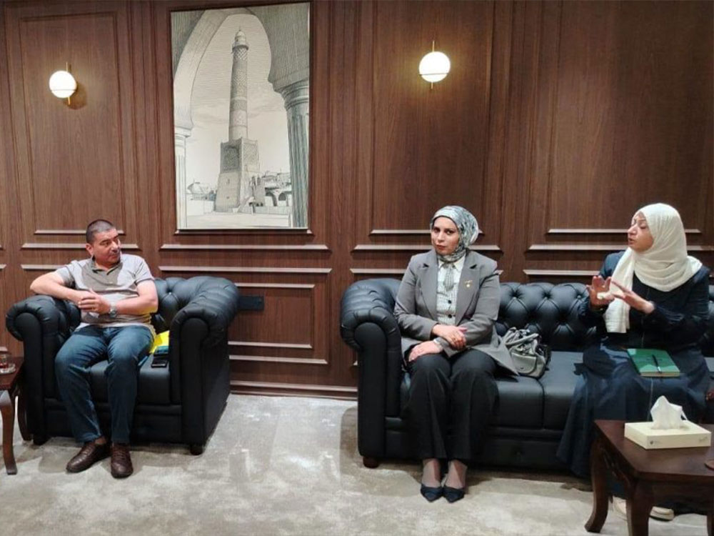 ثلاثة مسؤولين يجلسون داخل قاعة اجتماعات ذات جدران خشبية، خلال مناقشة ملف بيئي، وتظهر في الخلفية لوحة لمنارة الحدباء.