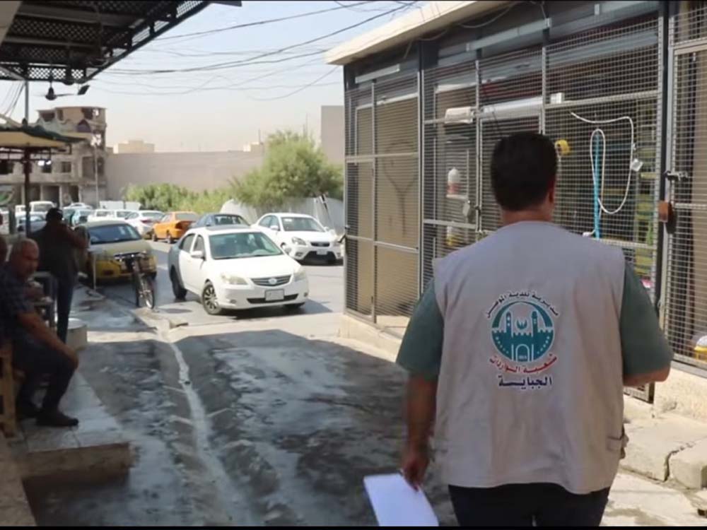 أحد موظفي بلدية الموصل يسير في أحد شوارع المدينة القديمة حاملاً أوراقاً رسمية، ضمن حملة ميدانية لتبليغ أصحاب المحال التجارية بضرورة مراجعة البلدية وتسديد مستحقات الجباية.