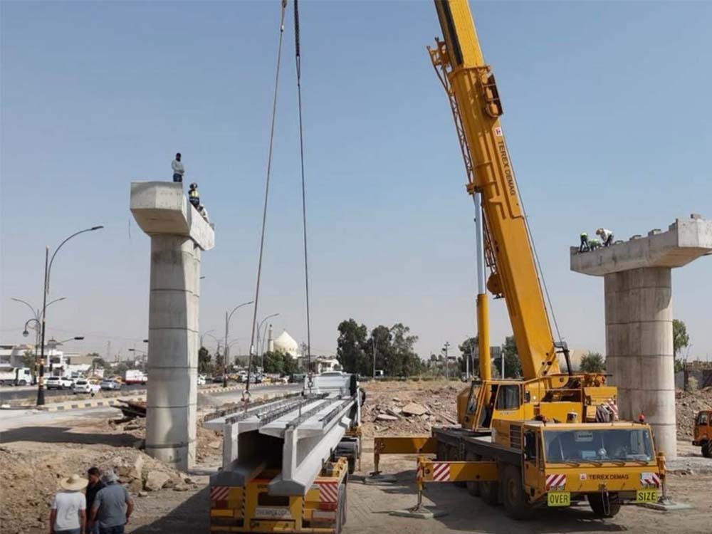 رافعة إنشائية تعمل على تركيب روافد الجسر الرئيس ضمن مشروع تقاطع الصابرين المجسر في مدينة الموصل، مع ظهور الأعمدة الخرسانية وأعمال التنفيذ الجارية في الموقع.