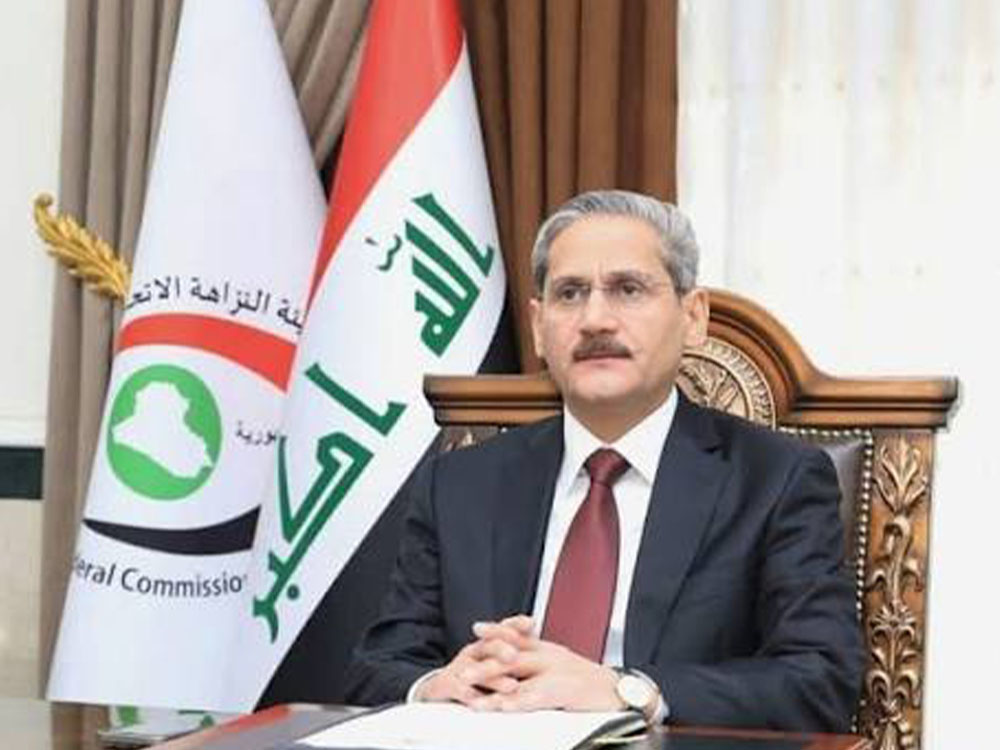 رئيس هيئة النزاهة الاتحادية العراقية الدكتور محمد علي اللامي يجلس خلف مكتبه، وأمامه العلم العراقي وعلم الهيئة.