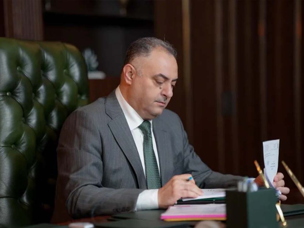 مدير بلدية الموصل محمد الآغا يجلس خلف مكتبه داخل مقر البلدية، يراجع وثائق رسمية ويقوم بتدوين ملاحظات أثناء متابعة الملفات الإدارية.