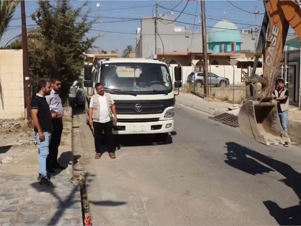 آلية إنشائية تزيل تجاوزاً على أحد الشوارع والأرصفة في مدينة الموصل