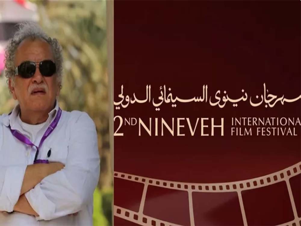 المخرج المصري أشرف فايق بجانب شعار مهرجان نينوى السينمائي الدولي في الموصل