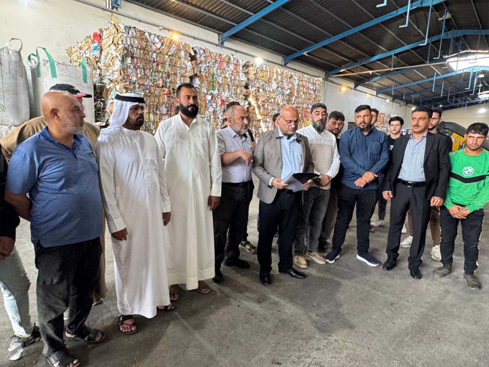 عاملون في مجال جمع وكبس مخلفات الكرتون خلال وقفة احتجاجية داخل أحد معامل إعادة التدوير في الموصل