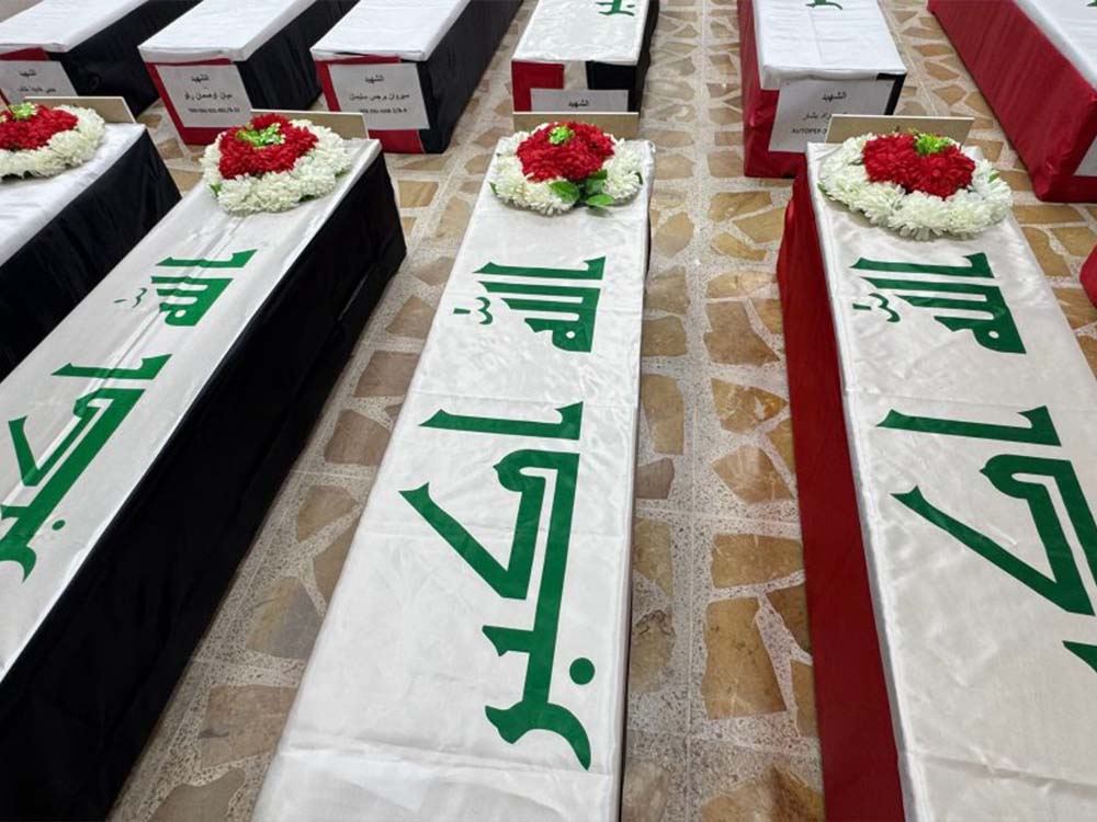 توابيت ضحايا مجزرة سنجار مغطاة بالعلم العراقي ومزينة بالزهور تمهيداً لتسليم الرفات إلى ذويهم