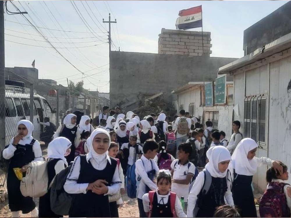 طلاب وطالبات أمام إحدى المدارس العراقية أثناء توجههم إلى الدراسة