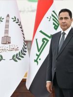 محافظ نينوى عبد القادر الدخيل يقف أمام العلم العراقي وعلم محافظة نينوى