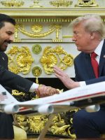 الرئيس الأميركي دونالد ترمب يصافح مسؤولاً عراقياً خلال لقاء في البيت الأبيض، وأمامهما نموذج لطائرة، في مشهد يعكس العلاقات العراقية الأميركية.