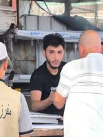 عنصر من مفرزة التجاوزات يرتدي سترة مخصصة يقف أمام أحد أصحاب المحال التجارية أثناء توجيه إنذار له في الموصل.