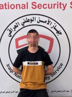 متهم بوجه مموّه يجثو أمام شعار جهاز الأمن الوطني العراقي، عقب إلقاء القبض عليه في محافظة نينوى.