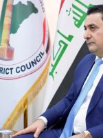 قائممقام الموصل يجلس في مكتبه وإلى جانبه العلم العراقي وشعار مجلس قضاء الموصل.