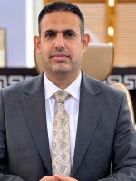 محمد مظهر البياتي المكلف بإدارة مديرية تحقيق هيئة النزاهة في محافظة نينوى، يرتدي بدلة رسمية داخل مكتبه.