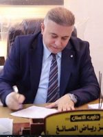 مدير شعبة الرقابة الصحية في نينوى عزيز رياض الصائغ يجلس خلف مكتبه أثناء توقيعه على عدد من الوثائق الرسمية.