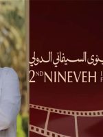 المخرج المصري أشرف فايق بجانب شعار مهرجان نينوى السينمائي الدولي في الموصل